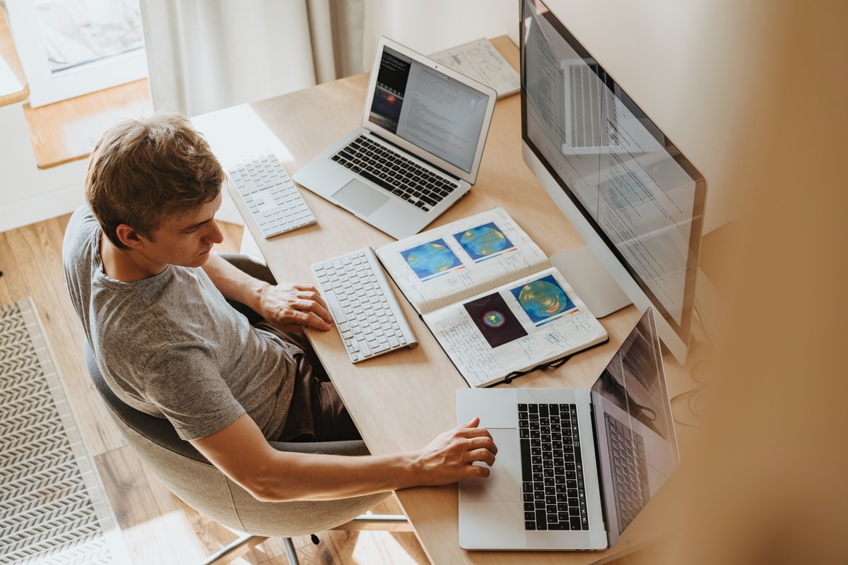 A man working from home with 3 computers